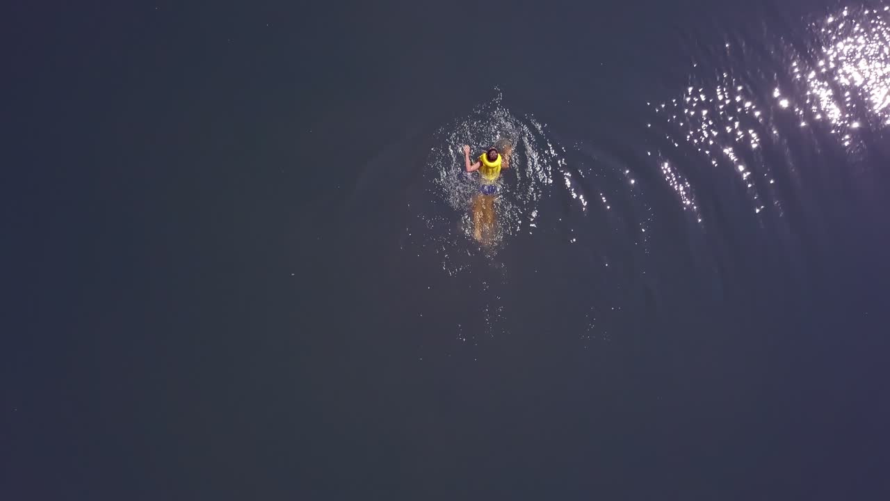 Boy swims in the river in summer. Happy children on summer vacation. Aerial view.