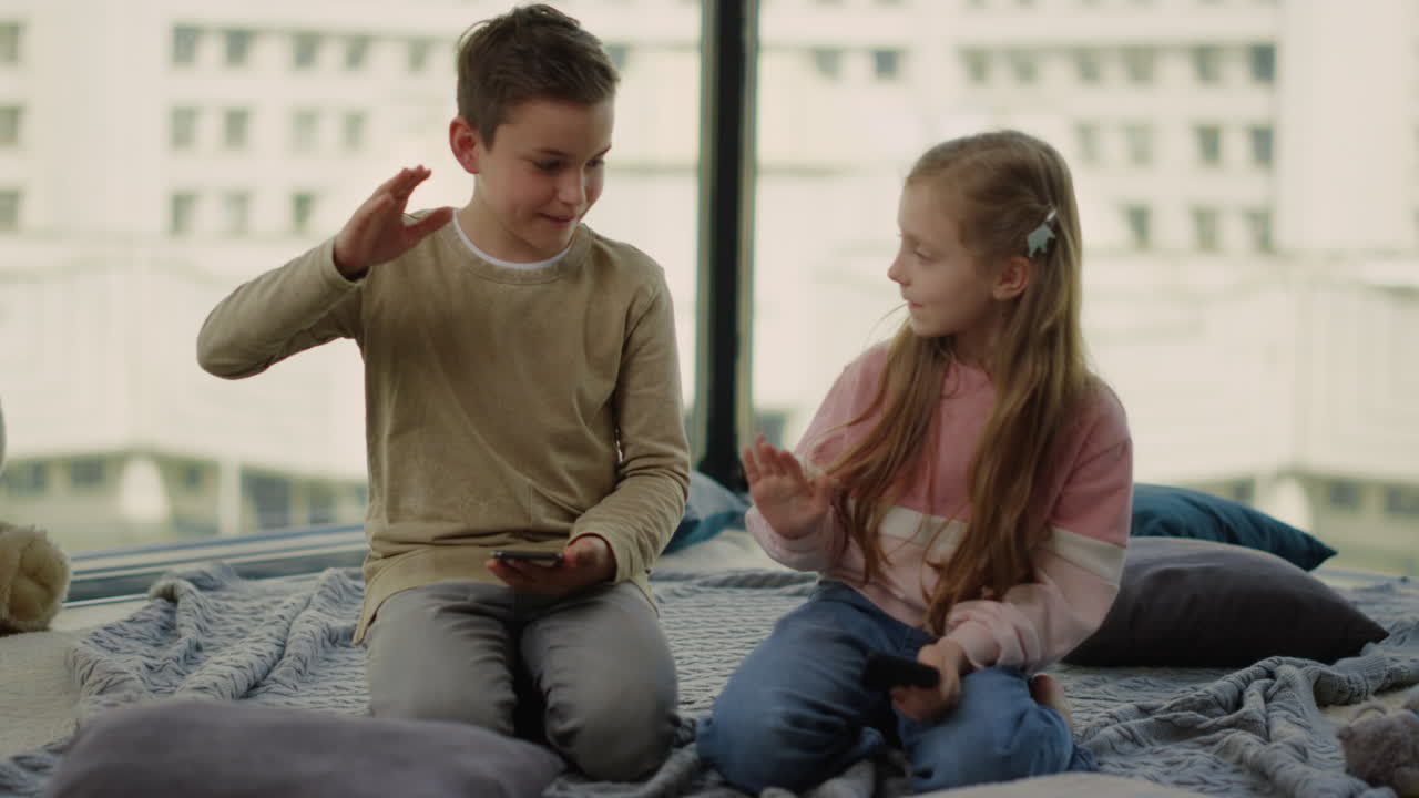 Children sitting on floor with cell phones. Siblings playing mobile games.