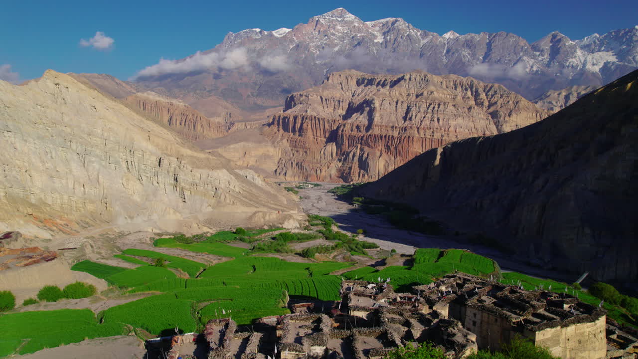 Drone shot captures beautiful Chusang village in Upper Mustang, Nepal. Unique structured dry mountains, snowy peaks, and a captivating blue sky backdrop. Explore the allure of Annapurna Area