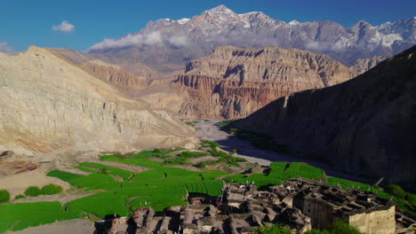 drone shot captures beautiful chusang village in upper mustang, nepal. unique structured dry mountains, snowy peaks, and a captivating blue sky backdrop. explore the allure of annapurna area