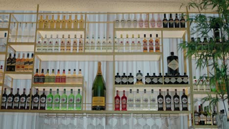 liquor and wine bottles are neatly arranged on modern bar shelves.
