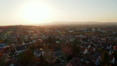 Aerial-drone-view-of-small-town-against-setting-sun.-Calm-evening-atmosphere.-Bad-Vilbel,-Germany.