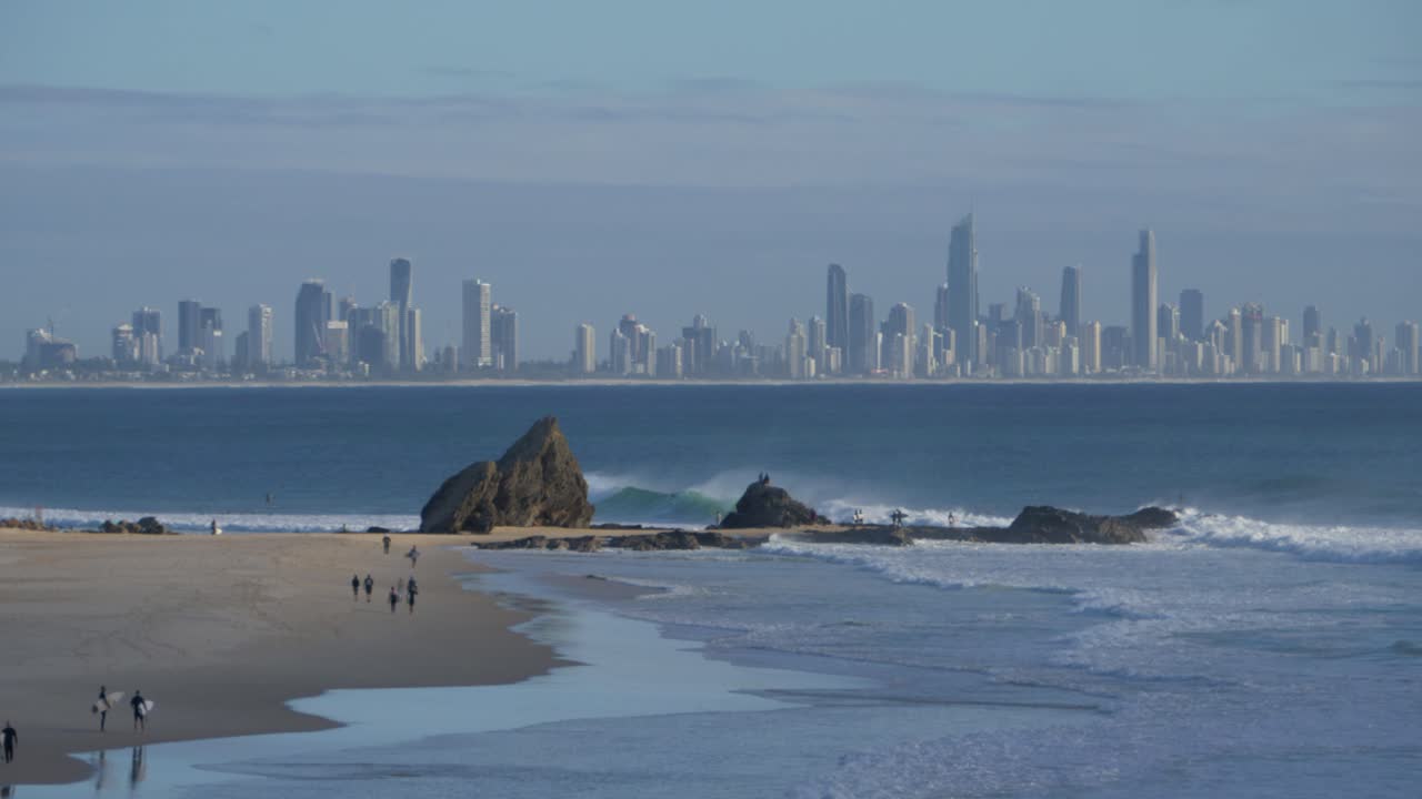 surfistas en la playa de currumbin - vista del horizonte de la costa dorada en el fondo - queensland, australia - plano general