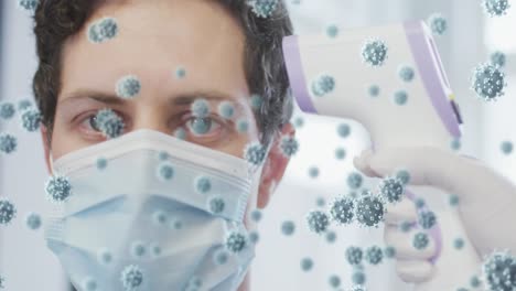 Animation-of-covid-19-cells-over-man-in-face-mask,-having-temperature-checked