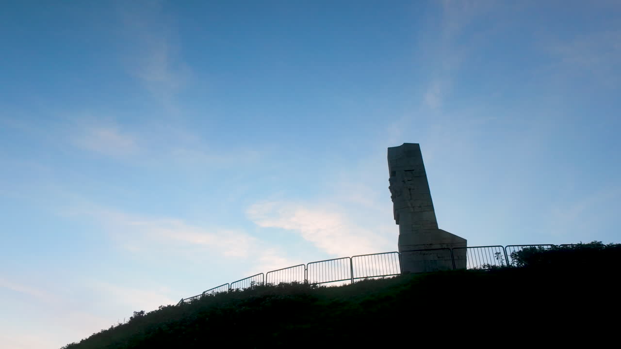 Monument silhouette on hilltop against vibrant evening sky, symbolizing remembrance and resilience at sunset