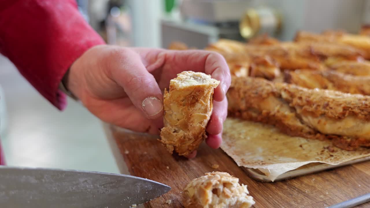 Close-up of a baker slicing fresh pastry to reveal its crispy interior