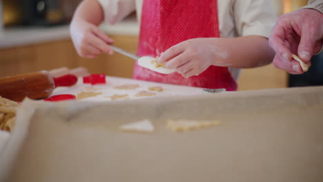 dad and boy arrange gingerbread cookies cut out of dough on a baking sheet