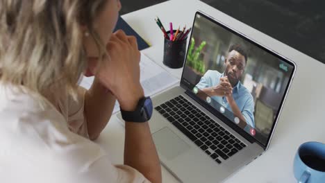 video de una mujer caucásica haciendo una videollamada en una computadora portátil con un compañero de trabajo afroamericano