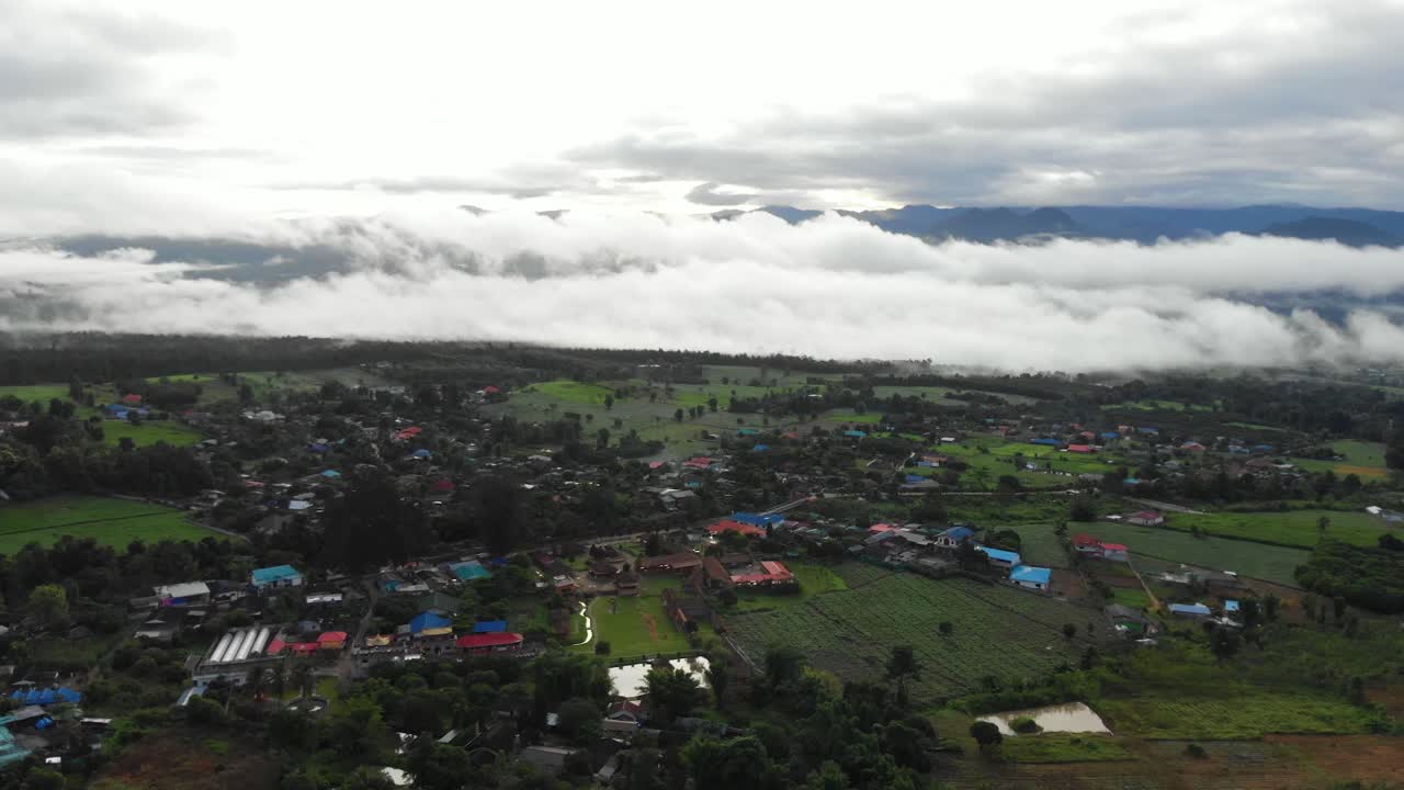 무인 항공기는 몬순 시즌 동안 두꺼운 구름으로 덮인 작은 판잣집과 작은 마을의 집과 들판으로 덮인 태국 파이의 외딴 시골 언덕 위로 날아갑니다.