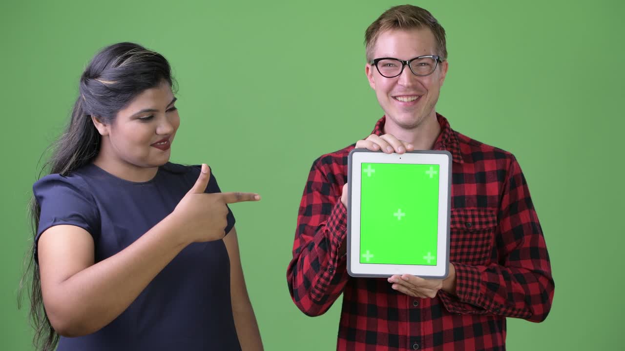 Young multi-ethnic business couple together against green background