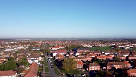 Aerial-rising-boom-shot-showing-the-landscape-over-a-countryside-village-in-southeast-England,-bright-blue-sky-day