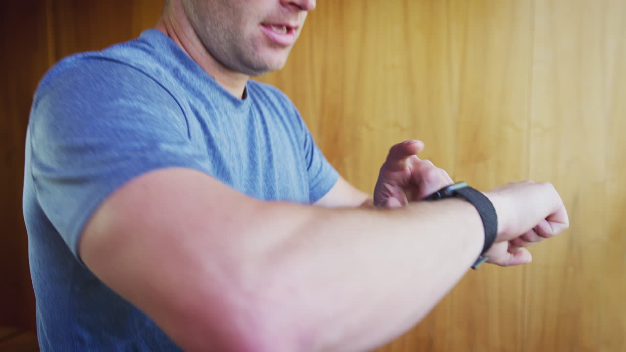 Primo piano di un uomo che si allena sul tapis roulant controllando lo smartwatch