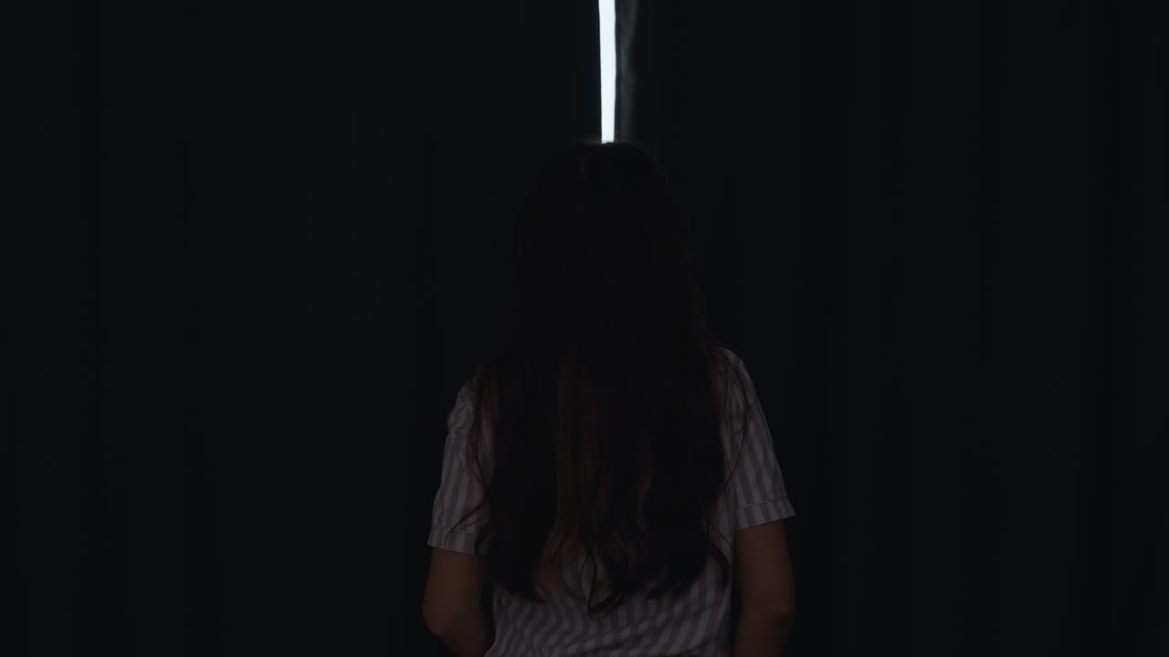 O amanhecer revela a cidade através das cortinas da janela, a luz da manhã ilumina a paisagem urbana movimentada além das cortinas, a mulher observa o nascer do sol enquanto a luz do sol ilumina a cidade atrás das cortinas fechadas