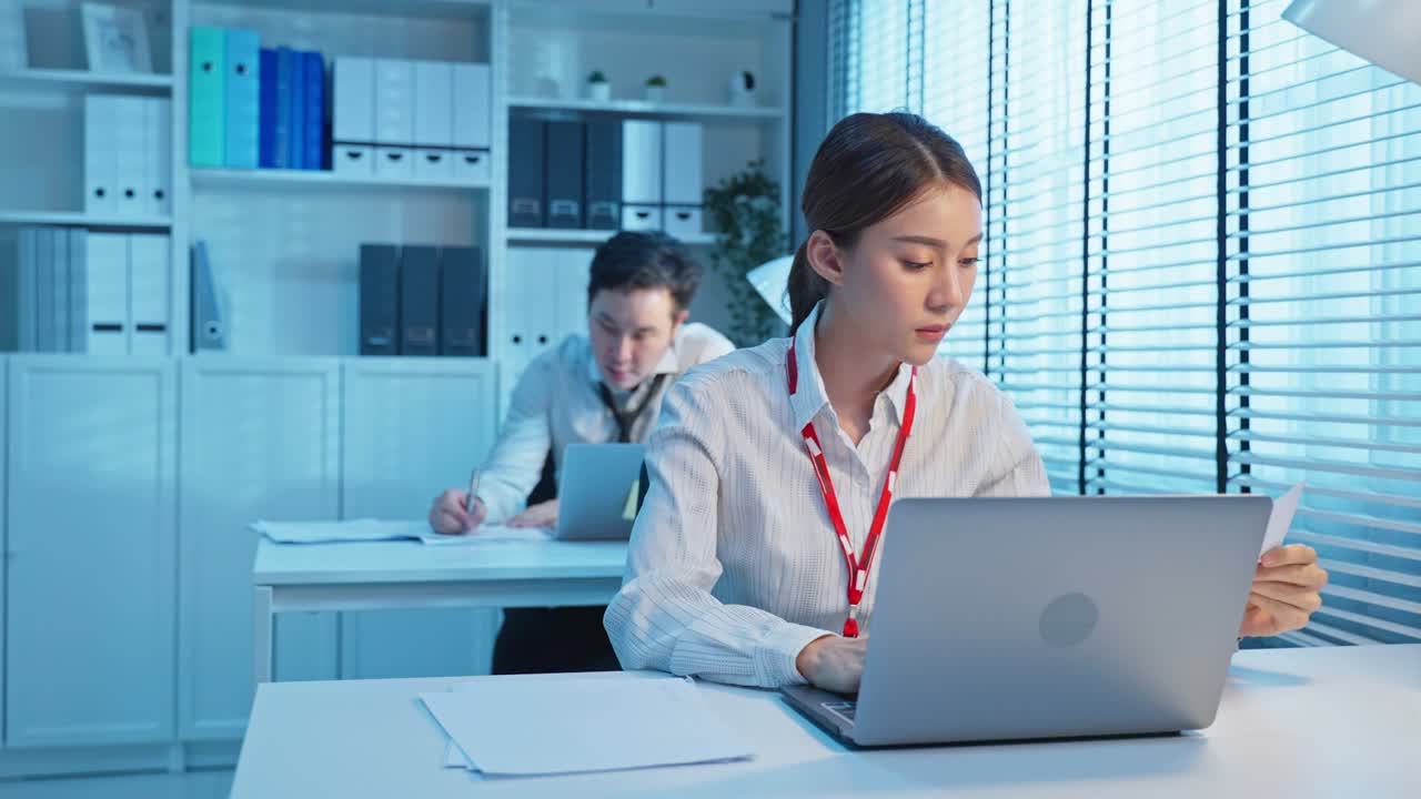joven hombre de negocios asiático y mujer grupo de trabajo en la oficina en la noche. empleado de la oficina trabajador sentado en la mesa, el uso de la computadora portátil trabajar juntos como trabajo en equipo en horas extras. corporativo de colegas modernos trabajo tarde.