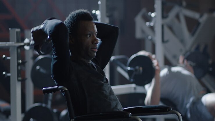 Man in Wheelchair Lifting Weights at Gym Confident Man in Wheelchair Performs Shoulder Press Exercise with Dumbbells at Modern Gym Demonstrating Strength Fitness and Determination