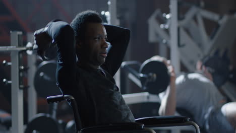 man in wheelchair lifting weights at gym confident man in wheelchair performs shoulder press exercise with dumbbells at modern gym demonstrating strength fitness and determination