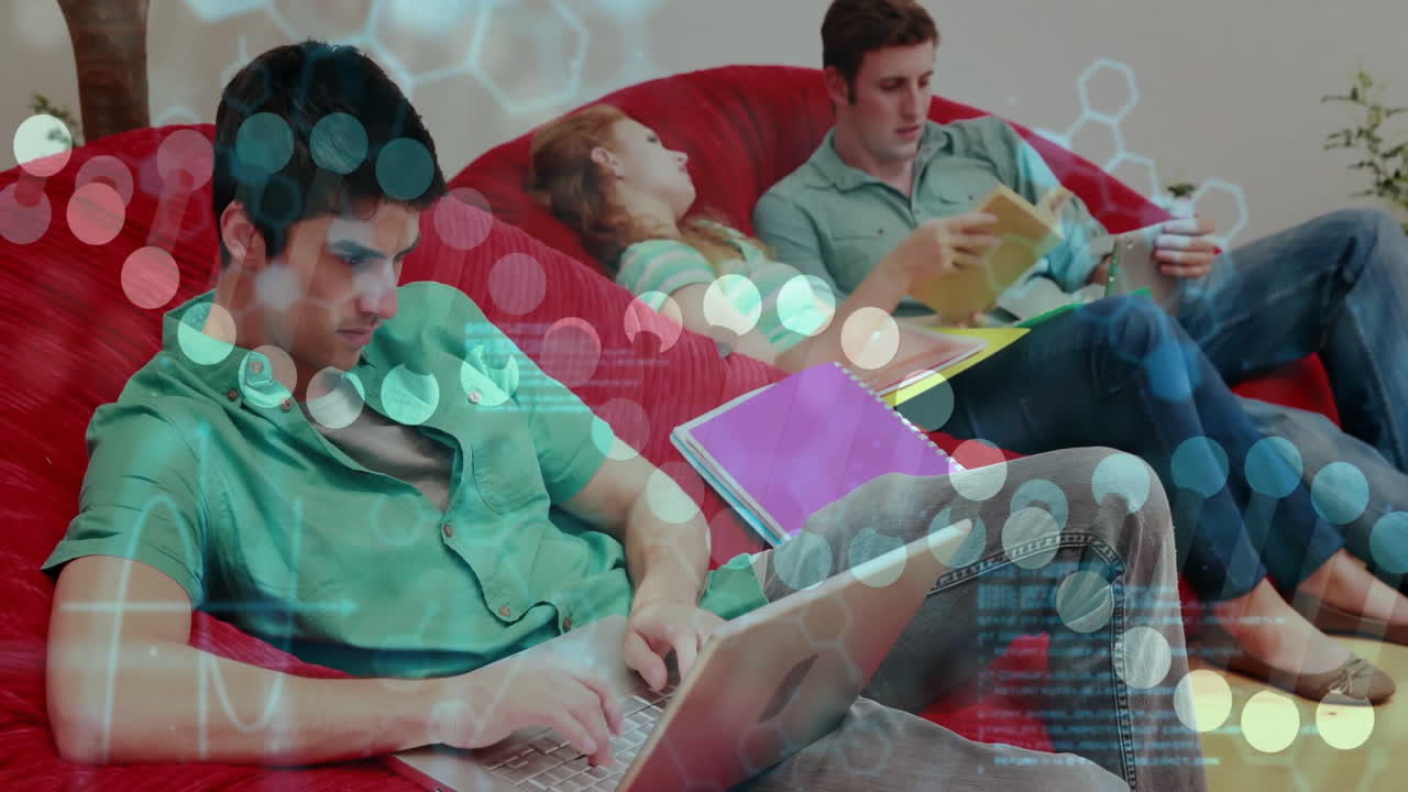 Group lounging on red sofa, typing on laptop, flipping tablet, showing data overlays for education