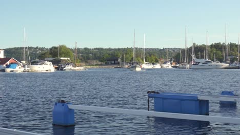 Yacht-Kommt-Am-Yachthafen-In-Kragero-An,-Im-Hintergrund-Liegen-Segelboote-Vor-Anker