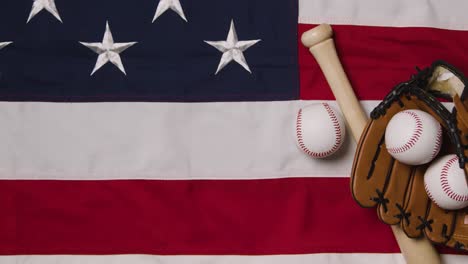 overhead baseball still life with bat and catchers mitt on american flag with person picking up ball