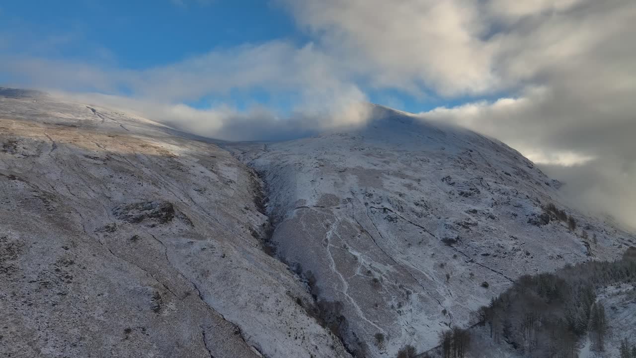 laderas de montañas en nieve ligera con aumento de altitud hacia nubes en movimiento
