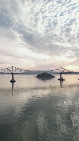 A static drone view captures the Richmond-San Mateo Bridge stretching across the shimmering waters of San Francisco Bay.