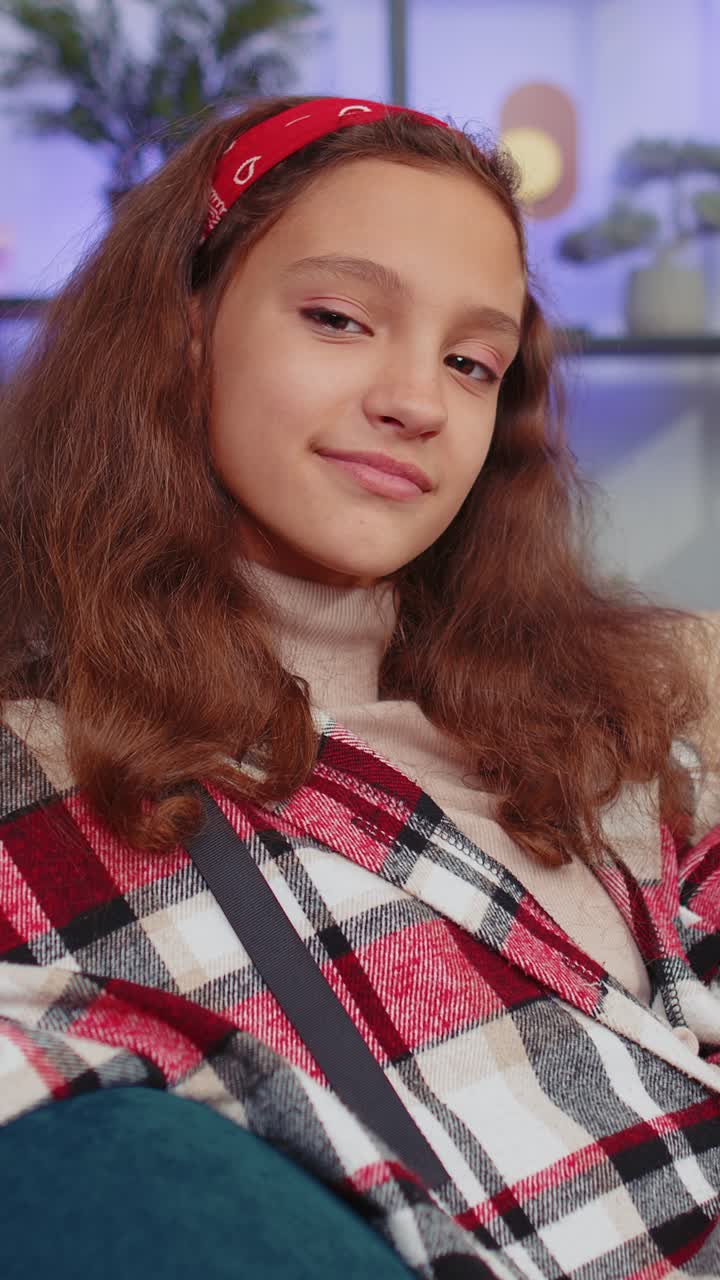 Primo piano di bambina preadolescente studentessa felice e bella, sorridente mentre guarda la fotocamera a casa sul divano.