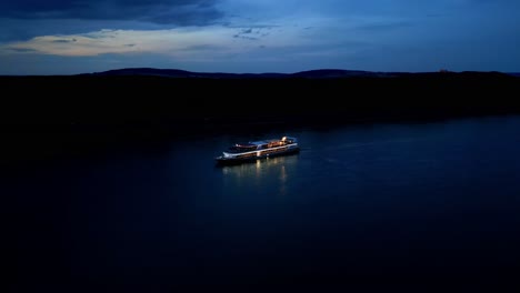 Aerial-View-Of-Ship-Cruising-Danube-River-At-Night---drone-shot