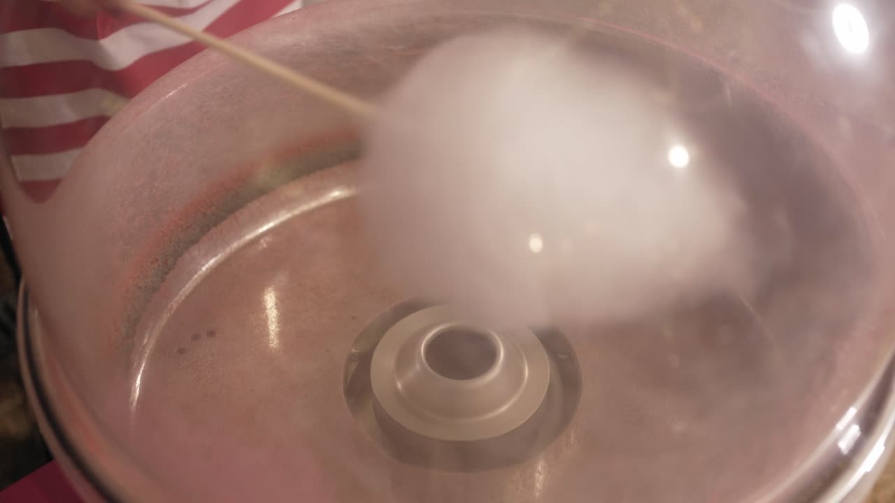 Close up of cotton candy machine spinning sugar in a festive setting indoors
