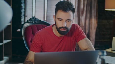hombre enfocado trabajando en una computadora portátil en el lugar de trabajo en el hogar.