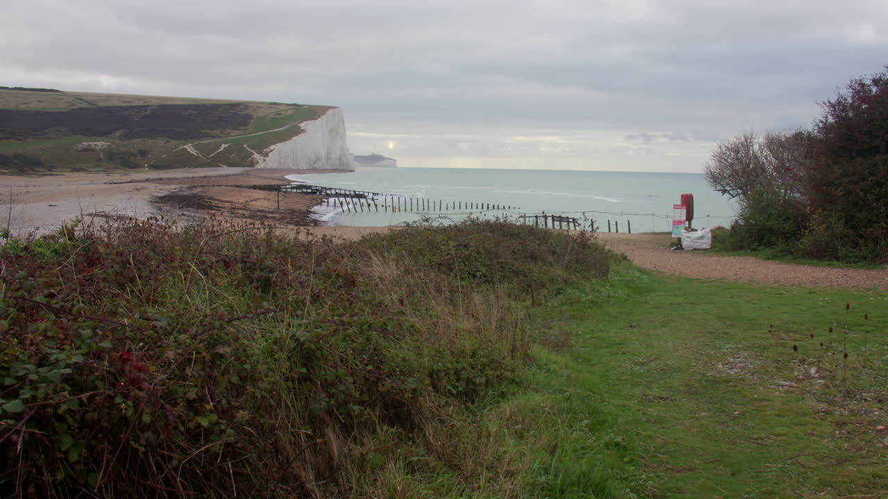 Tomada ampla dos penhascos Seven Sisters com trilha que desce para Seaford Head
