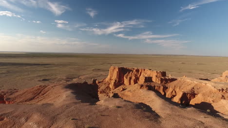 Man-standing-on-the-edge-of-flaming-cliffs-Bayanzag-aerial-drone-shot-Mongolia