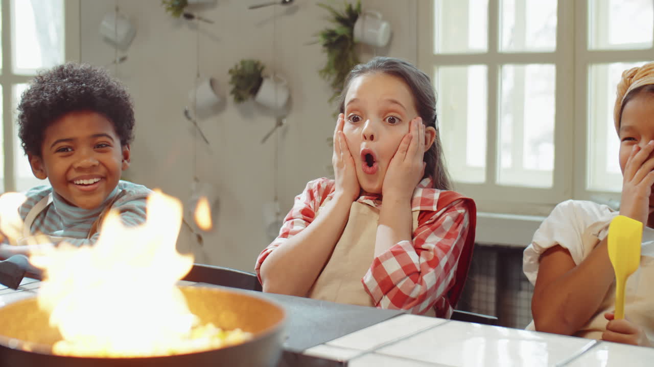niños asombrados mirando la comida flambeando en la clase maestra de cocina
