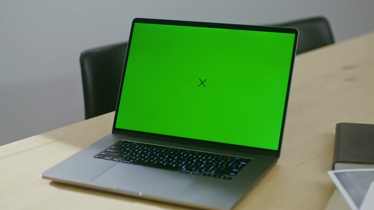 un portatile aperto con uno schermo verde si trova sul desktop dell'architetto