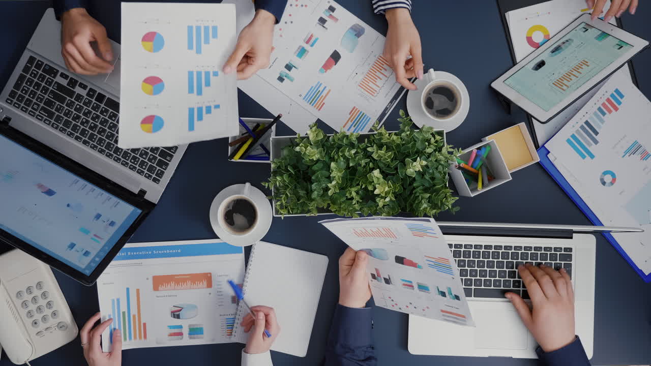 Top view of teamwork sharing financial company paperwork discussing management statistics