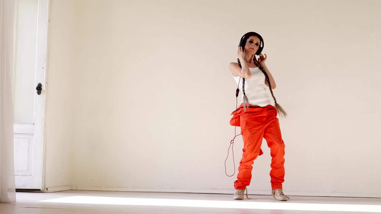 a woman with pigtails listens to music with headphones and dancing