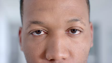 portrait of happy biracial male doctor wearing looking at camera in corridor, slow motion