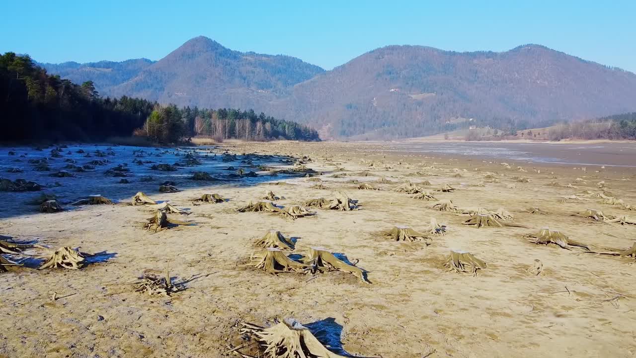 Drone flying low over the lake with cracks and crevices filled with scanty water on sunny day