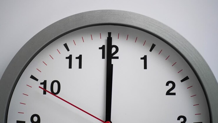 Close up of a ticking clock on white background, pointing midnight