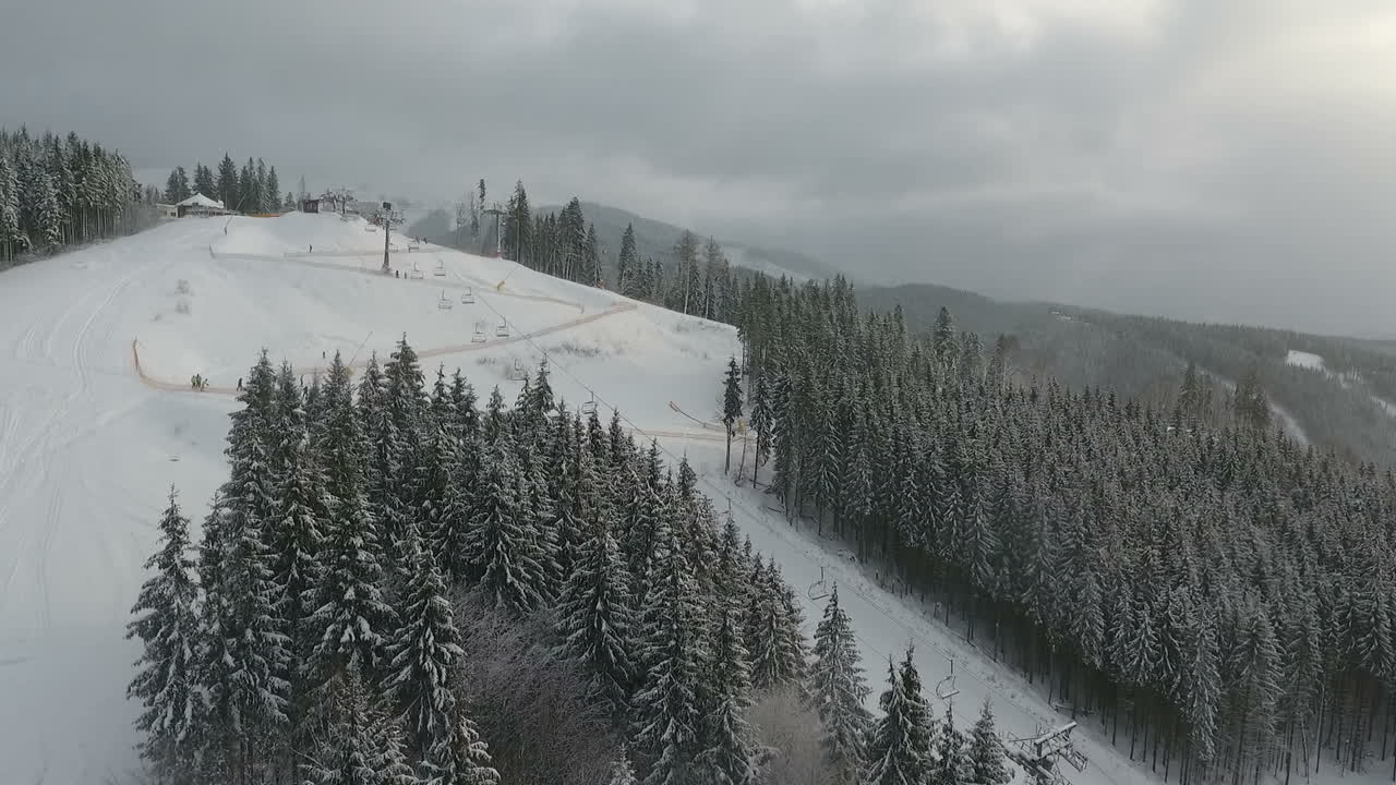 Skiers and snowboarders go down the slope in a ski resort. Winter forest. Aerial view