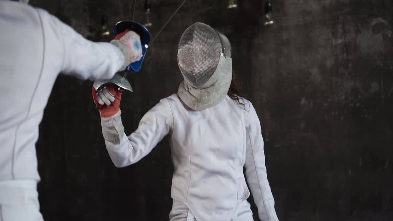 두 명의 펜싱 선수가 행동하고 있습니다.