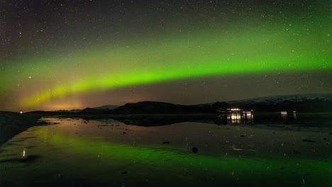 Lapso-De-Tiempo-Estático-De-Aurora-Boreal-Junto-Al-Lago-Con-Vehículos-En-La-Carretera-En-Islandia-Por-La-Noche---Plano-General