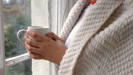 Mujer-Con-Una-Taza-De-Café-Parada-Cerca-De-La-Ventana