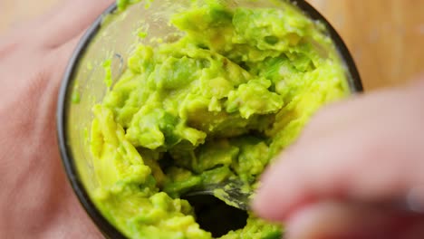 mixing mashing avocado puree in glass with spoon, close up