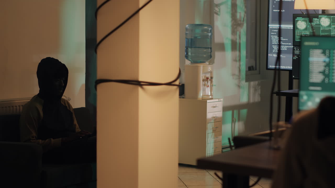 Office with a water cooler and a hacker working on a computer