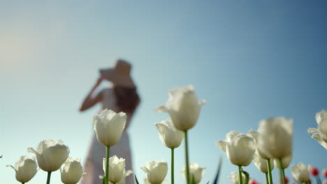 Woman-silhouette-wearing-hat-in-flower-garden.-Unrecognizable-girl-on-vacation.