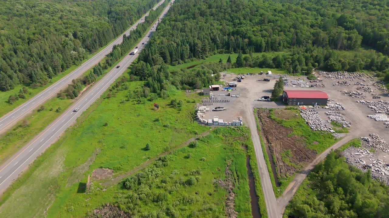 Drone flyover of Muskoka gravel pit bordered by forest with green terrain and dirt roads