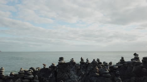 aerial: drone sliding besides stacks of rock cairns next to the ocean in tropical queensland, australia