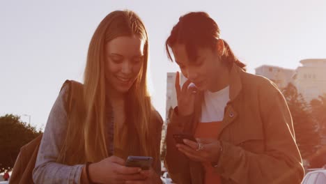 side view of a caucasian and a mixed race girl using their phone