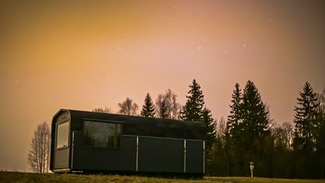 cinematic time lapse of wooden house in nature during stunning northern lights and flying stars at night sky