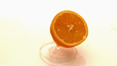 Orange-half-falling-and-bouncing-on-white-wet-surface